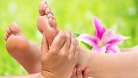 A message therapist massages a person's feet out in nature